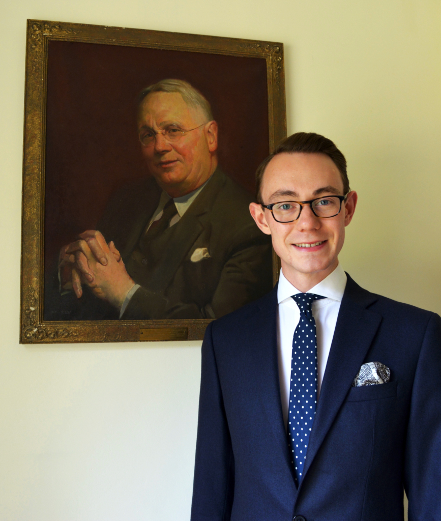 Nicholas Bowman Scargill, in front of a portrait of Amos Reginald Fear, 3rd MD of the Company.
